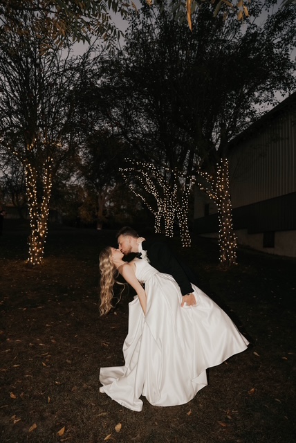Bride and groom dancing among trees wrapped in warm lights