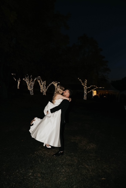 Bride and groom sharing a moment among lit trees at night