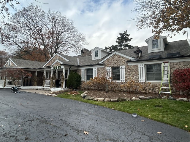 Daytime view of a home mid-installation with ladder and roofline lighting in progress